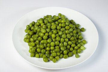 Pickled green peas on a white plate on a white background
