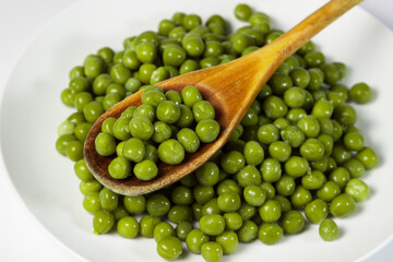 Pickled green peas on a white plate on a white background
