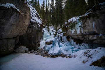 view from inside maligne river canyon on frozen waterfall with blue water