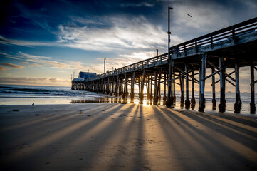 Fototapeta na wymiar Beautiful view of the pier at Newport Beach over sandy beach under cloudy sky, California