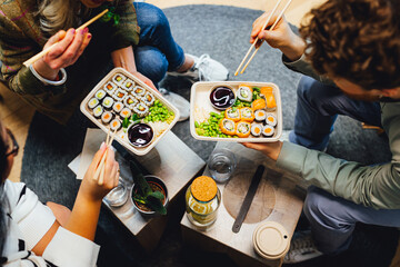 People having lunch, group of friends having sushi, eating asian food.