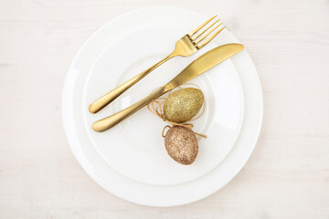 Easter table setting, Golden Easter eggs decoration, napkin and gold cutlery on plates