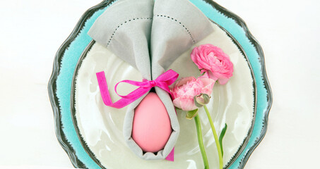 Easter table setting and decoration, Easter egg in a gray napkin on plates