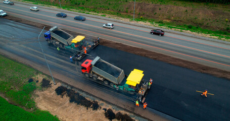 Road construction works aerial view. Laying of new asphalt on the road. The paver lays fresh asphalt, road rollers level and compact asphalt.  - obrazy, fototapety, plakaty