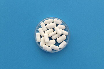 Medicine pills lie in a transparent container, top view.