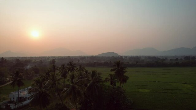 Aerial view of a sunset sky over rural rice fields with mountains in Visakhapatnam, India