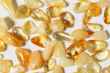 Amber stones on light background, transparent stone yellow beige color. Natural gemstone mineral material, healing crystal. Top view Amber textured fon. Nature gems, pieces ancient resin.