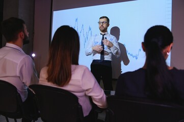 Obraz premium Man is standing near projector and showing graphs and business graphs.