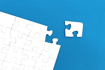 The game, a lot of white puzzle pieces lie on a blue background.	
