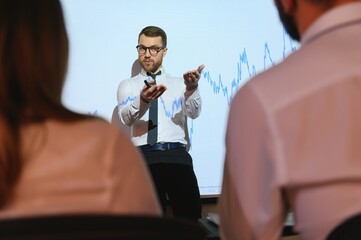 Trading teaching. Male leader talking to employees, showing the plan on the projector in office of stock exchange company.