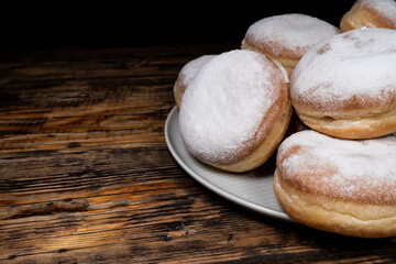 Polish pączki deep-fried doughnuts with copy space. Celebrating Fat Thursday (Tłusty czwartek) feast, traditional day in Poland. Pączek food, powdered sugar topped and filled with rose hip jam.