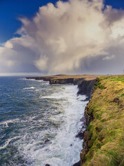 Beautiful scenery of Kilkee cliffs in county Clare, Ireland. Stunning Irish nature landscape. Day time, dramatic sky with clouds. Popular tourist and travel area with amazing view. Nature scene.