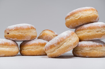 Polish pączki deep-fried doughnuts. Celebrating Fat Thursday, Tłusty czwartek feast, traditional day in Poland. Pączek food, powdered sugar topped and filled with rose hip jam.