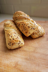 Panini rolls on a wooden board in a kitchen. Premium bread product with high quality and great taste. Healthy food. Vertical image.