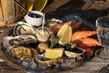 Fresh seafood platter (oysters, shrimp, bulot snails, shellfish, aioli) on the seafood restaurant outdoor terrace. Atmospheric seafood tasting at oyster farm in the south of France on a sunny day.