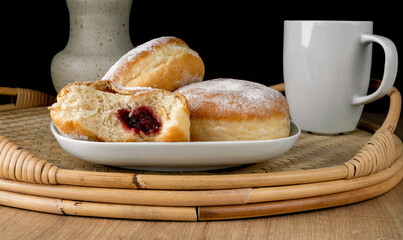 Polish pączki deep-fried doughnuts. Celebrating Fat Thursday, Tłusty czwartek feast, traditional day in Poland. Pączek food, powdered sugar topped and filled with rose hip jam.