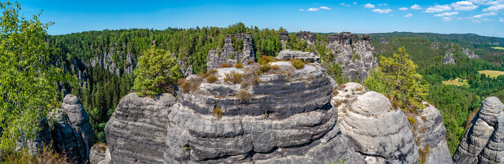 Panoramic over monumental Bastei sandstone pillars, rock formation and stacks surrounded by ancient...