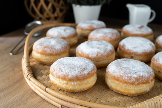 Polish pączki deep-fried doughnuts. Celebrating Fat Thursday, Tłusty czwartek feast, traditional day in Poland. Pączek food, powdered sugar topped and filled with rose hip jam.