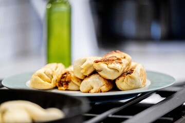Selective focus of burritos being fried on a black oven wrapped in tortillas