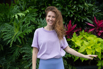 portrait of young girl on a green, natural background, eco friendly woman in a tropical park or jungle, positive lady enjoys walk at garden at summer day 