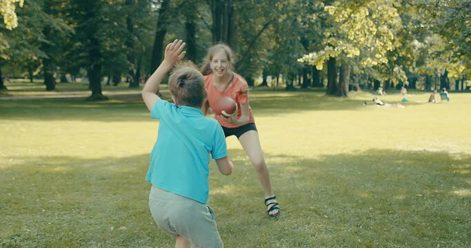 Happy family outdoors, Father and children play in football, Father's day, Playful Man teaching son and daughter rugby outdoors in sunny day at public park. Family sports weekend. 4K video