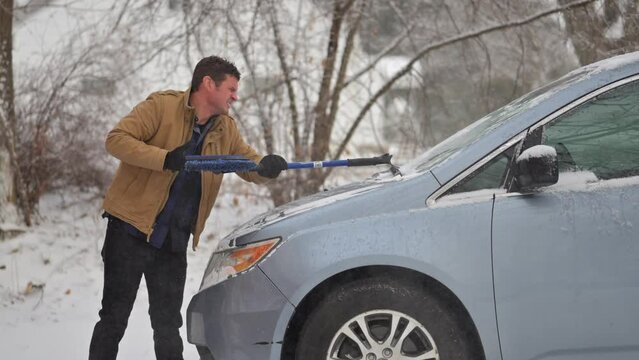 Caucasian man cleaning the snow off the car in the winter