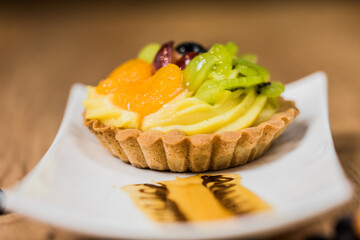 mini tart with custard and fresh fruits on a decorated plate