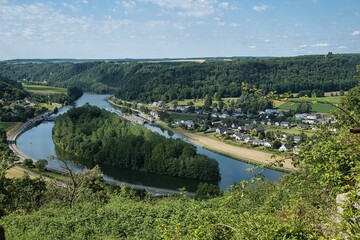 High-angle shot of Poilvache castle precinct with a lake and forested hills, blue sky background