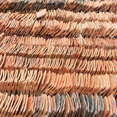 View of a pile of stacked terracotta roof tiles, on a sunny day