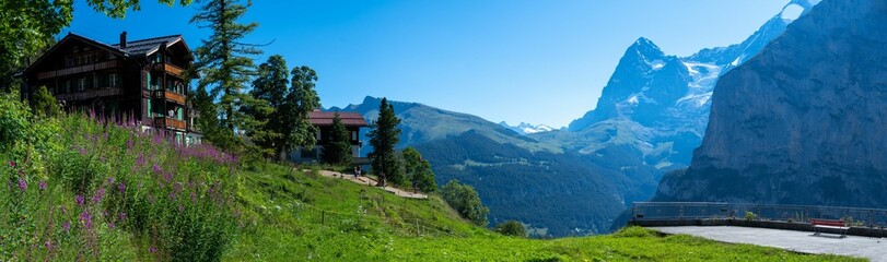 Panoramic shot of the house on top of the hill with mountains and trees in the background