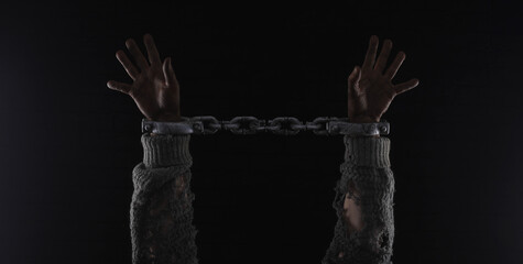 hands with prison chains, black brick wall