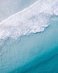 Vertical aerial shot of clear ocean water with foamy waves in Western Australia