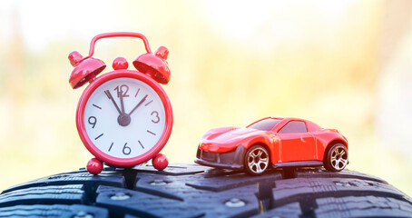 red alarm clock on winter tires, the concept of changing seasonal tires