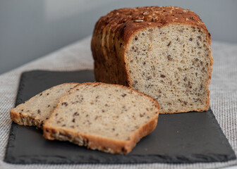Rye bread with seeds lies on a dark board on a light table. My home bakery. Organic whole grain bread. Bio Dinkel Brot. Healthy bread. complex carbohydrates. health diet. Healthy breakfast.