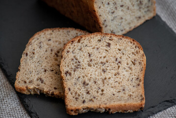 Rye bread with seeds lies on a dark board on a light table. My home bakery. Organic whole grain bread. Bio Dinkel Brot. Healthy bread. complex carbohydrates. health diet. Healthy breakfast.