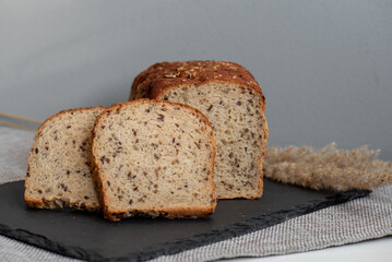 Rye bread with seeds lies on a dark board on a light table. My home bakery. Organic whole grain bread. Bio Dinkel Brot. Healthy bread. complex carbohydrates. health diet. Healthy breakfast.