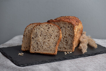 Rye bread with seeds lies on a dark board on a light table. My home bakery. Organic whole grain bread. Bio Dinkel Brot. Healthy bread. complex carbohydrates. health diet. Healthy breakfast.