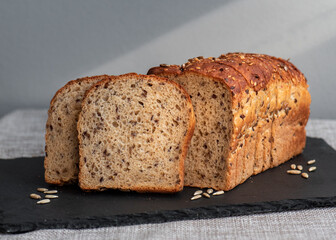 Rye bread with seeds lies on a dark board on a light table. My home bakery. Organic whole grain bread. Bio Dinkel Brot. Healthy bread. complex carbohydrates. health diet. Healthy breakfast.
