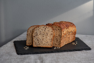 Rye bread with seeds lies on a dark board on a light table. My home bakery. Organic whole grain bread. Bio Dinkel Brot. Healthy bread. complex carbohydrates. health diet. Healthy breakfast.