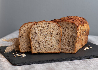Rye bread with seeds lies on a dark board on a light table. My home bakery. Organic whole grain bread. Bio Dinkel Brot. Healthy bread. complex carbohydrates. health diet. Healthy breakfast.