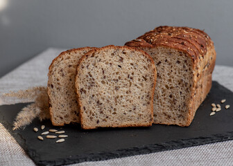 Rye bread with seeds lies on a dark board on a light table. My home bakery. Organic whole grain bread. Bio Dinkel Brot. Healthy bread. complex carbohydrates. health diet. Healthy breakfast.