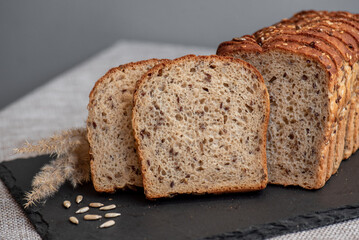 Rye bread with seeds lies on a dark board on a light table. My home bakery. Organic whole grain bread. Bio Dinkel Brot. Healthy bread. complex carbohydrates. health diet. Healthy breakfast.