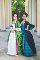 Two happy young beautiful women in long medieval dresses smile