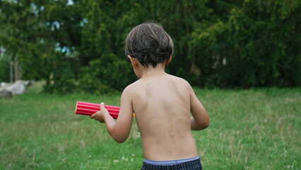 Back of child running outside in garden during summer day playing with kids water fight with toy foam guns