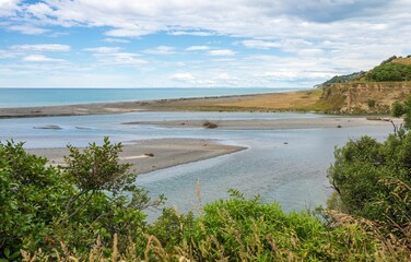 Fototapeta na wymiar Pebbles on Hurunui River Mouth under blue cloudy sky in South Island, New Zealand