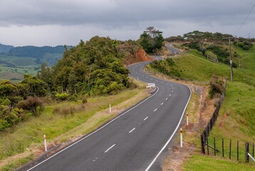 Beautiful view of a road on a hill with green trees under the blue sky