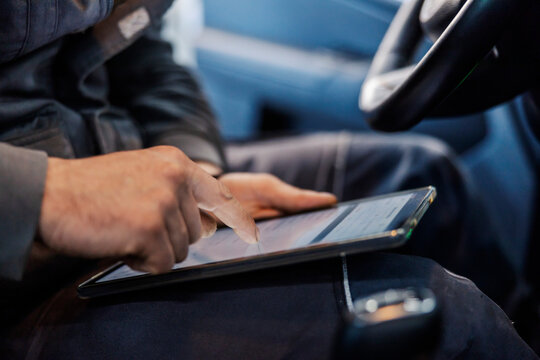 Hand scrolling on tablet and doing technical review at mechanic's shop.