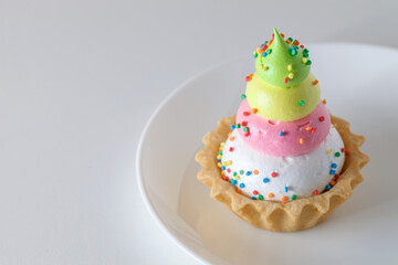 Cake basket tart with three-layer multicolored custard sweet sprinkles on white board background, selective focus
