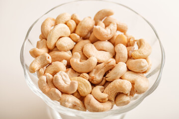 Cashew nuts poured in glass bowl, selective focus