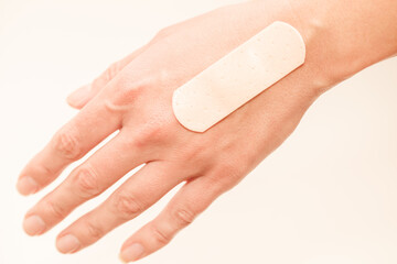 Medical band aid glued to woman hand with well-groomed skin, selective focus